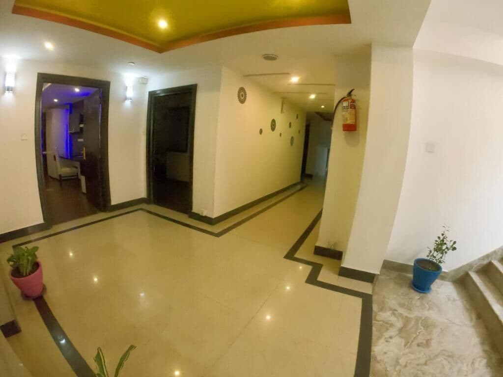 A spacious lobby with a polished floor, a fire extinguisher, and potted plants.