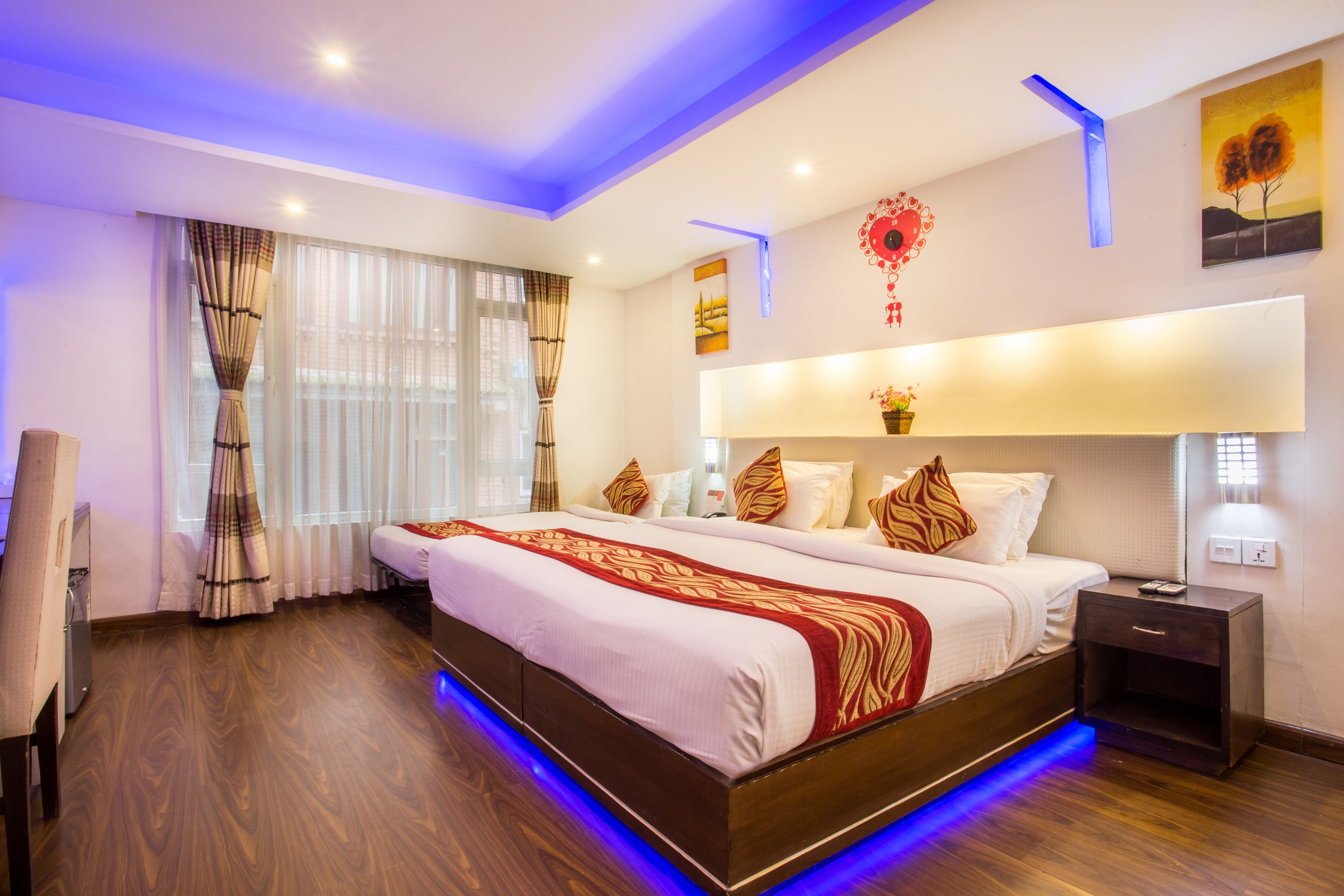 A modern hotel room with a large bed, wooden flooring, and a nightstand.