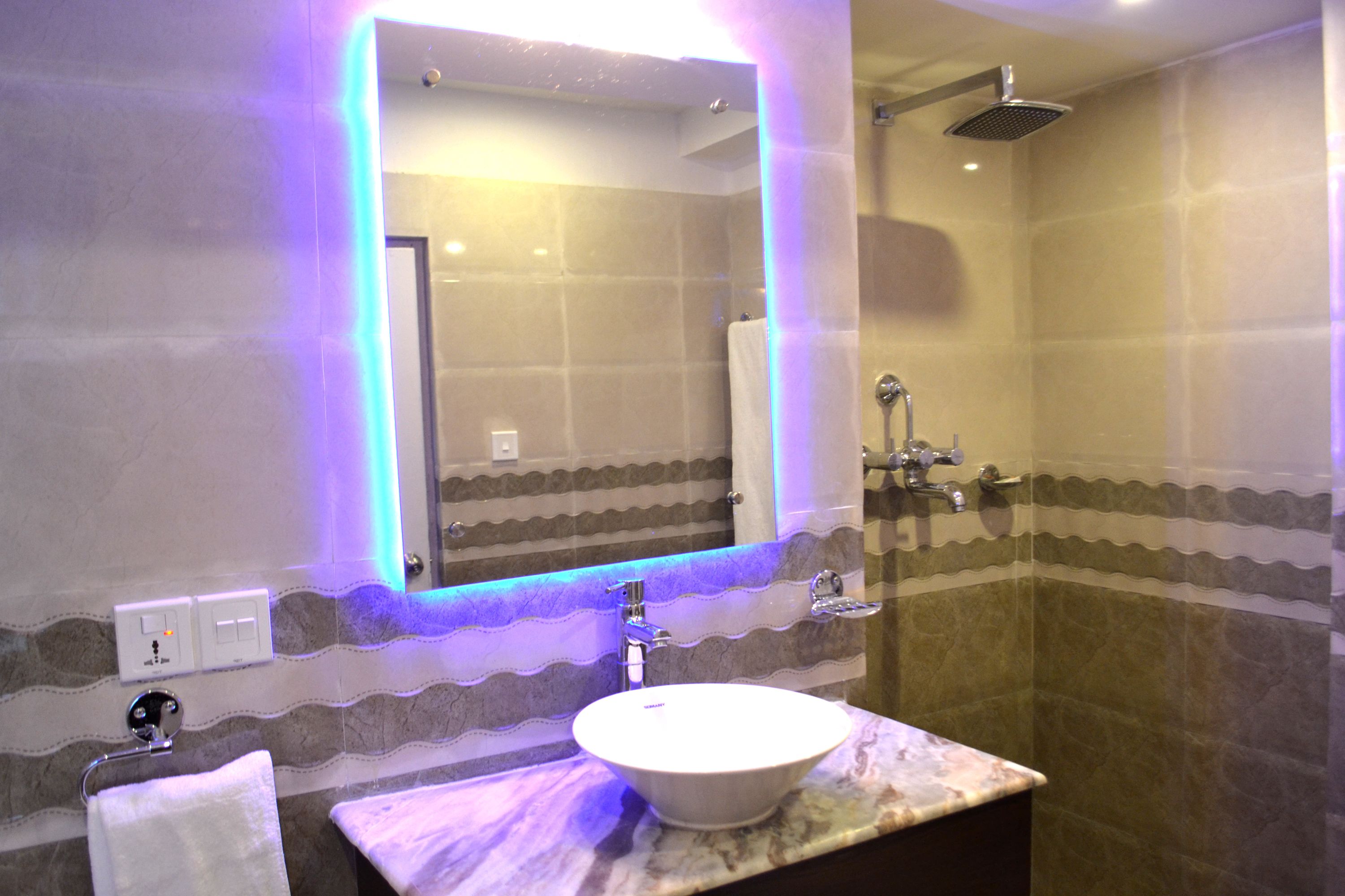 A bathroom with a marble sink, a large mirror, and a shower.