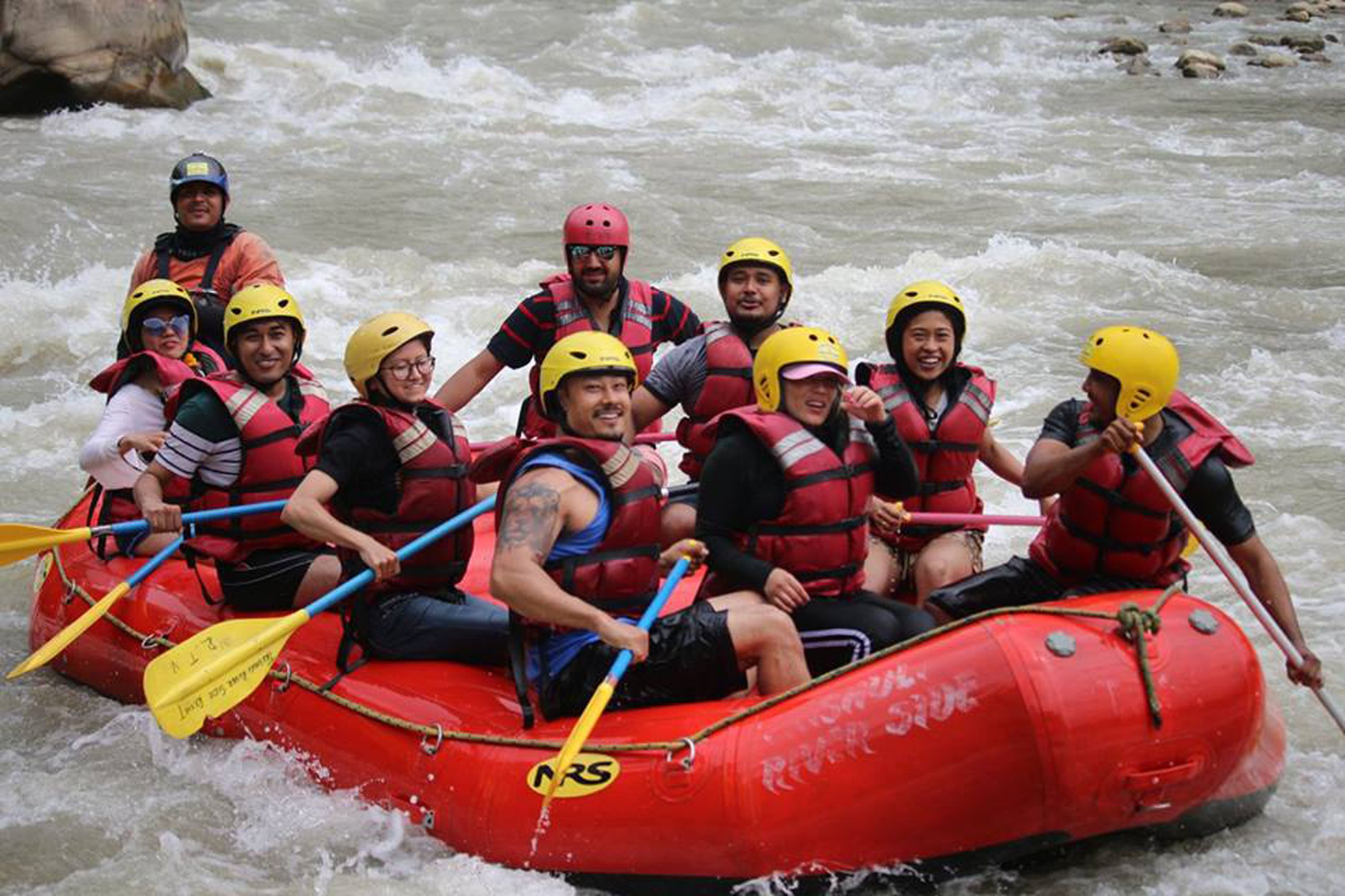 A group of people in a red inflatable raft on a river.