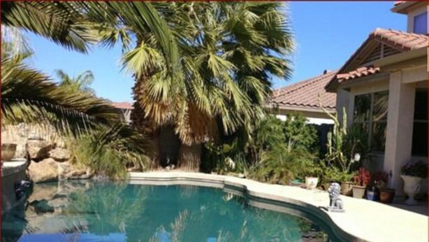 A swimming pool surrounded by palm trees and a building with a tiled roof. - Happy Valley House (Phoenix)