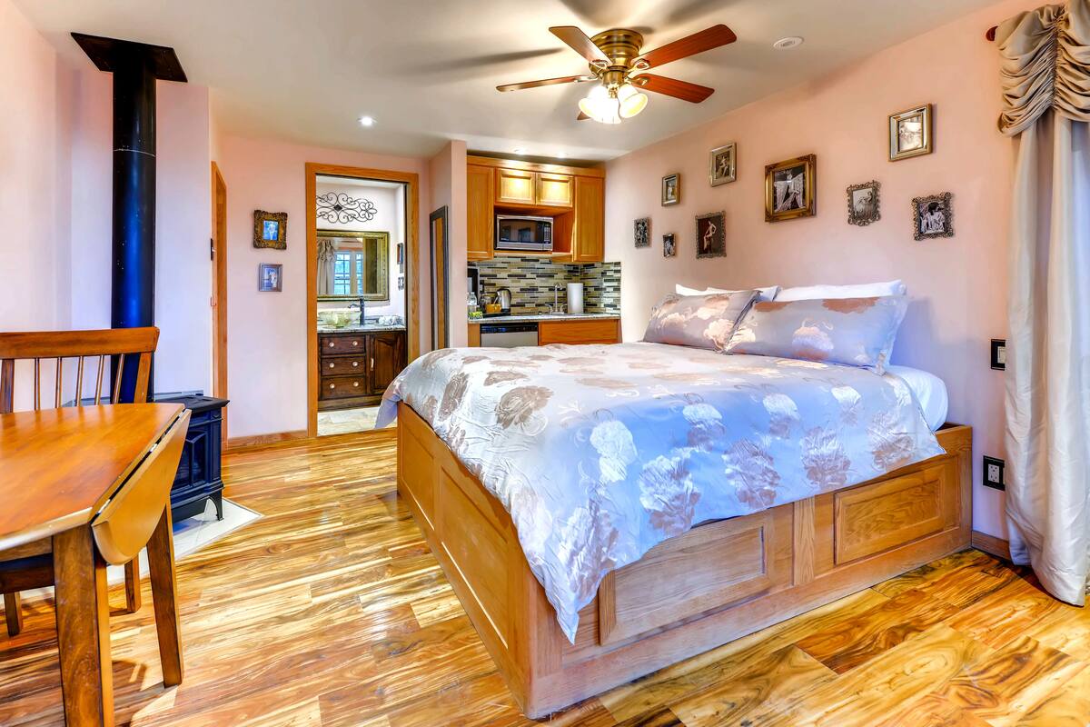Een slaapkamer met een houten bed, een eettafel en een keukenhoek.