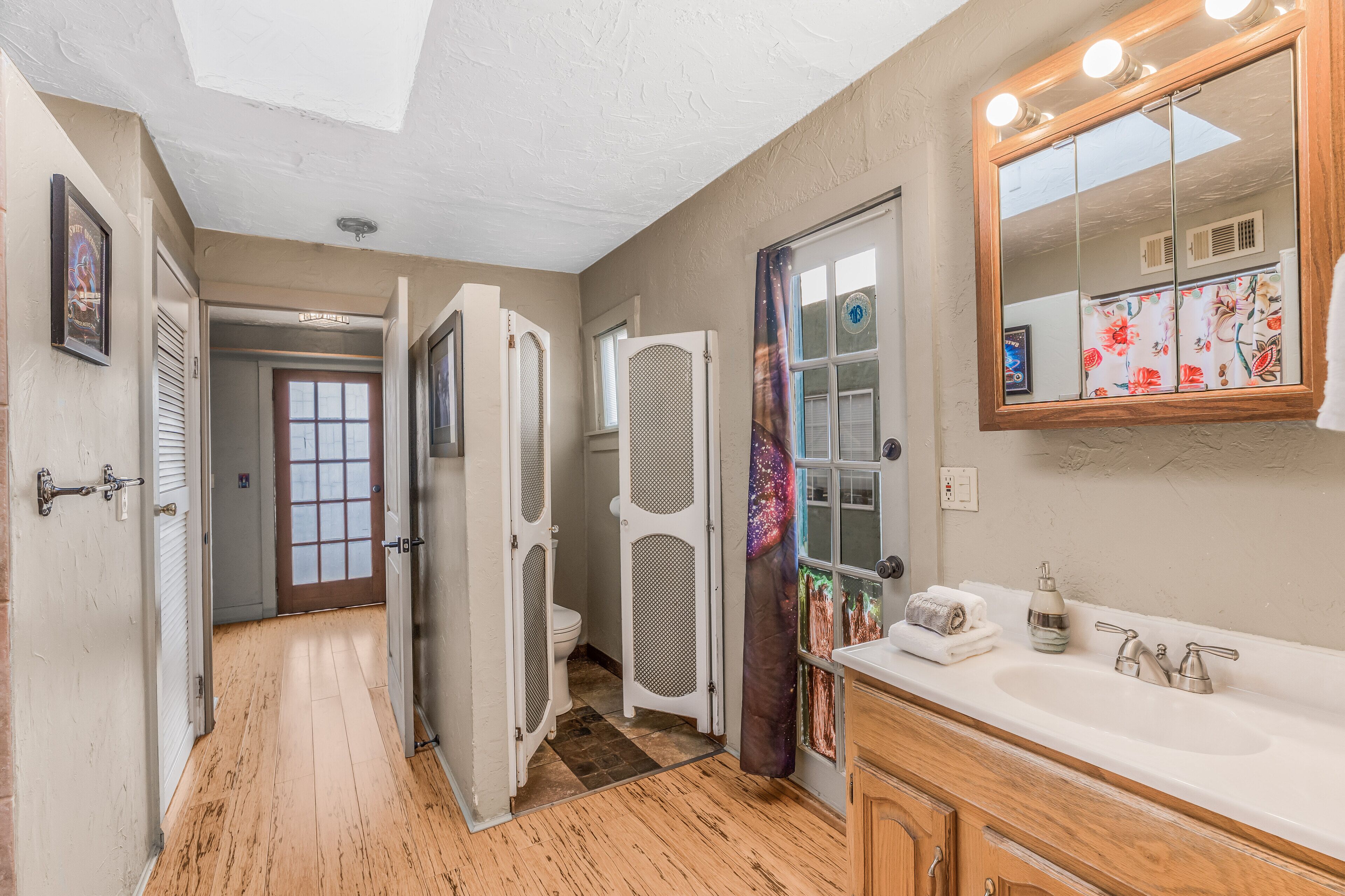 A bathroom with a wooden vanity, a large mirror, and a shower enclosure.
