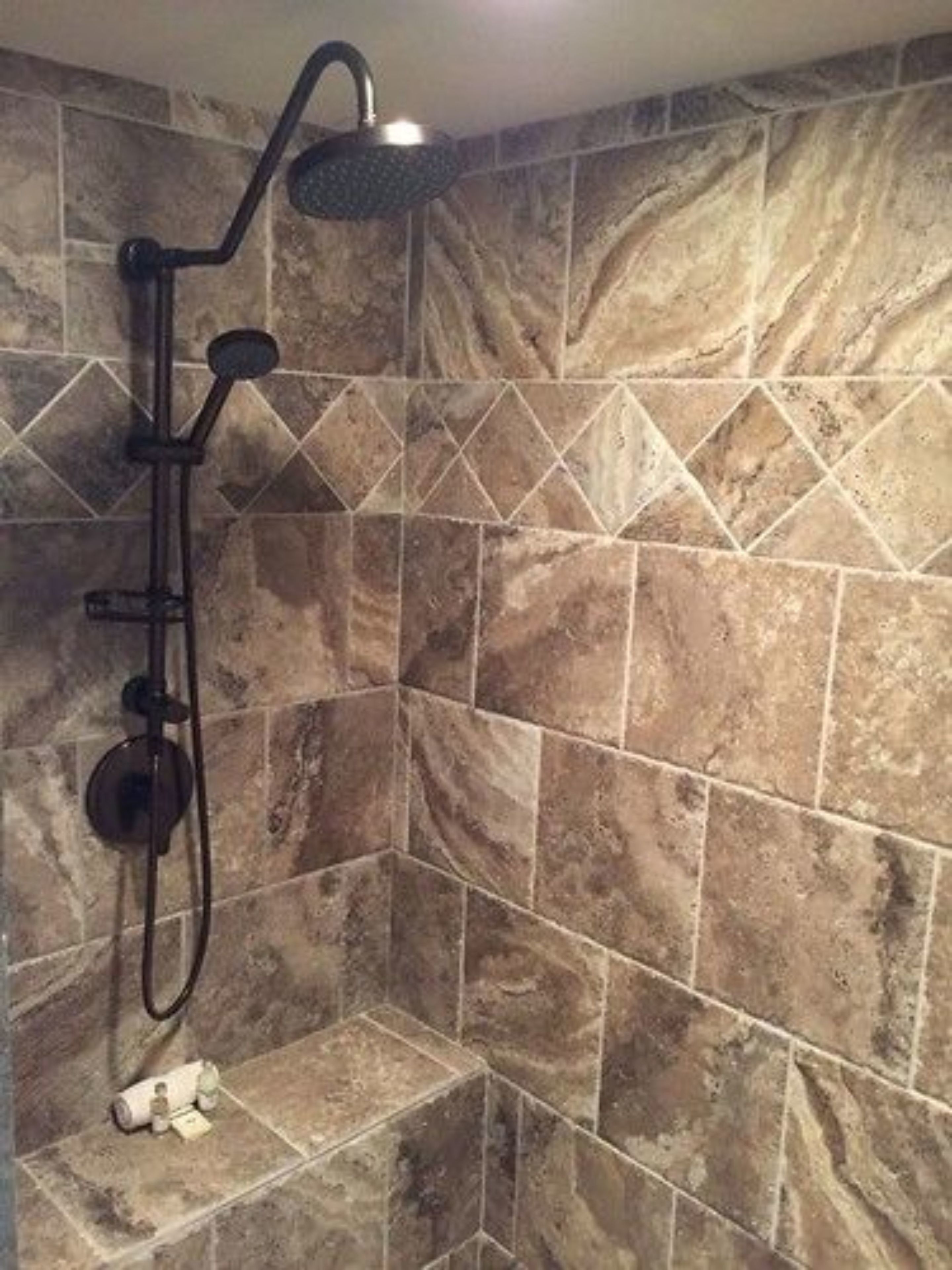Ducha con cabezal de ducha de mano y grifo empotrado en la pared, frente a un revestimiento cerámico con diseño geométrico.