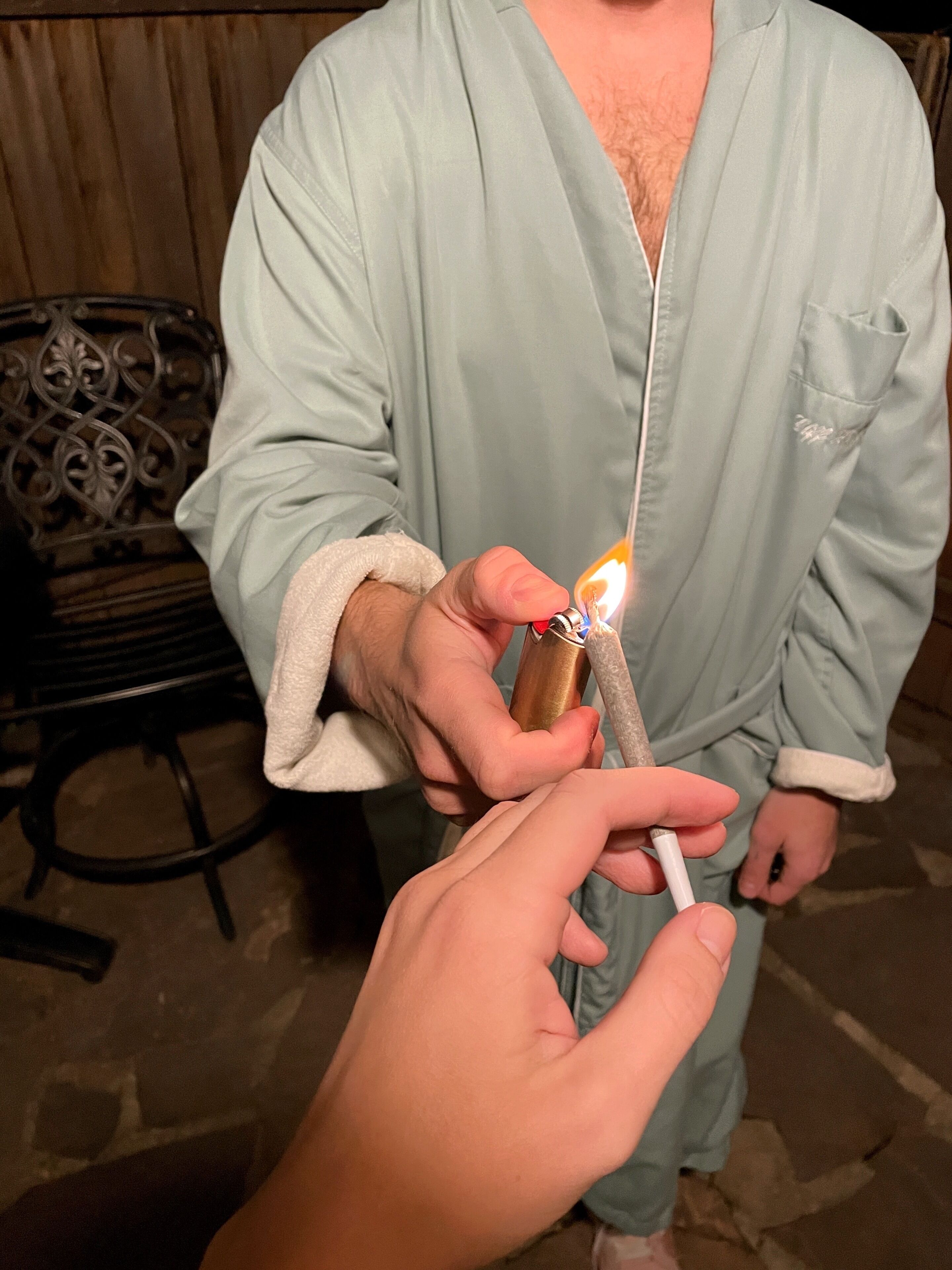 A person in a robe holding a lighter with a lit flame.