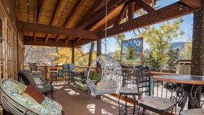 Un espacio de estar techado al aire libre con mobiliario de mimbre, una mesa y un espejo decorativo.