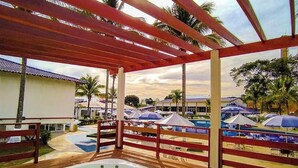 Una terraza de madera con un jacuzzi, sombrillas y vistas a una zona turística.