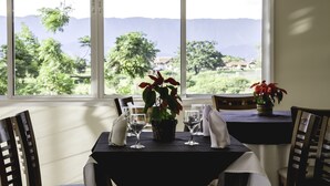 Una mesa de comedor con sillas, una planta en maceta y copas de vino preparadas para una comida.