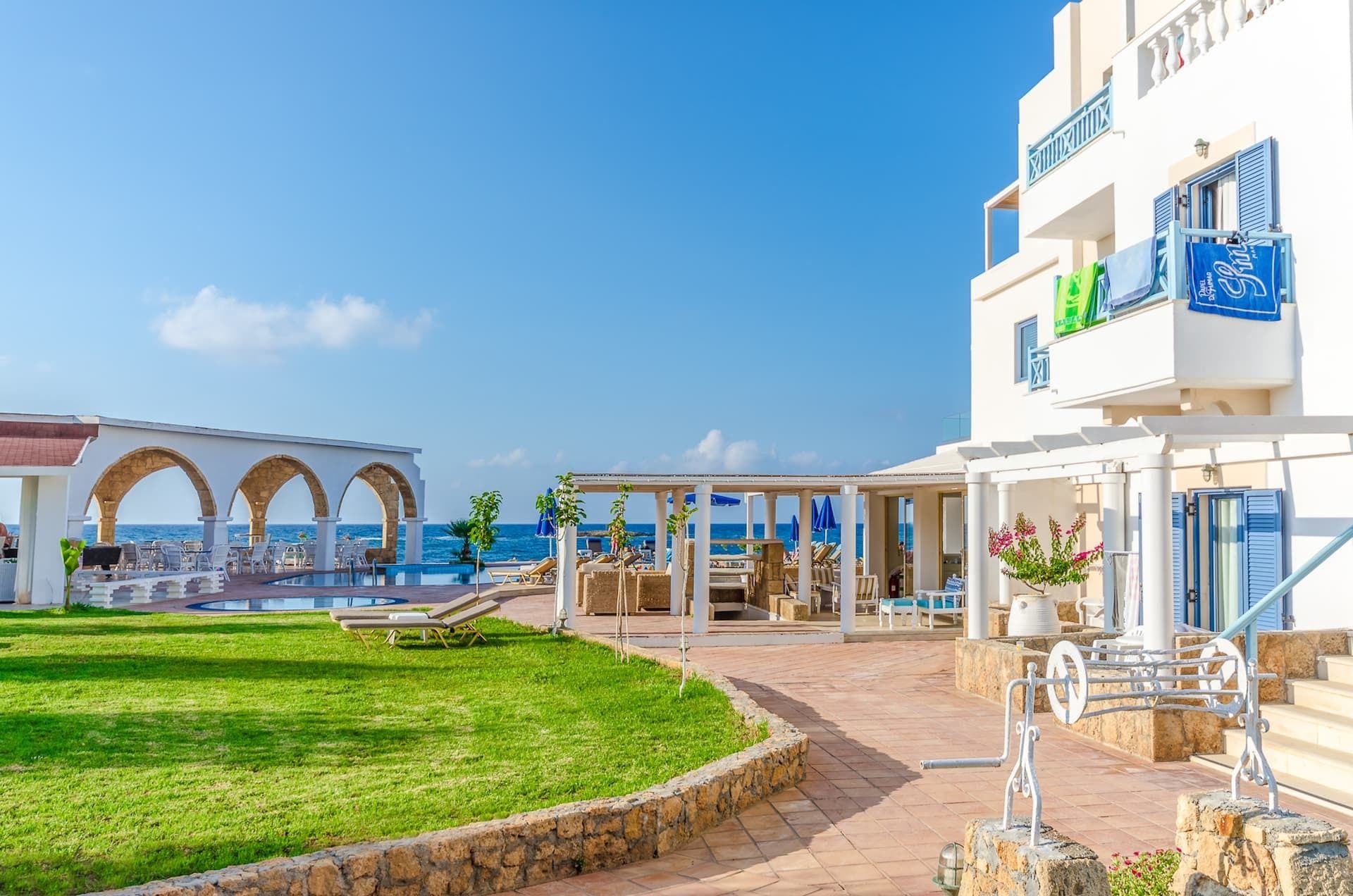 A resort with a pool, outdoor seating, and a view of the sea.