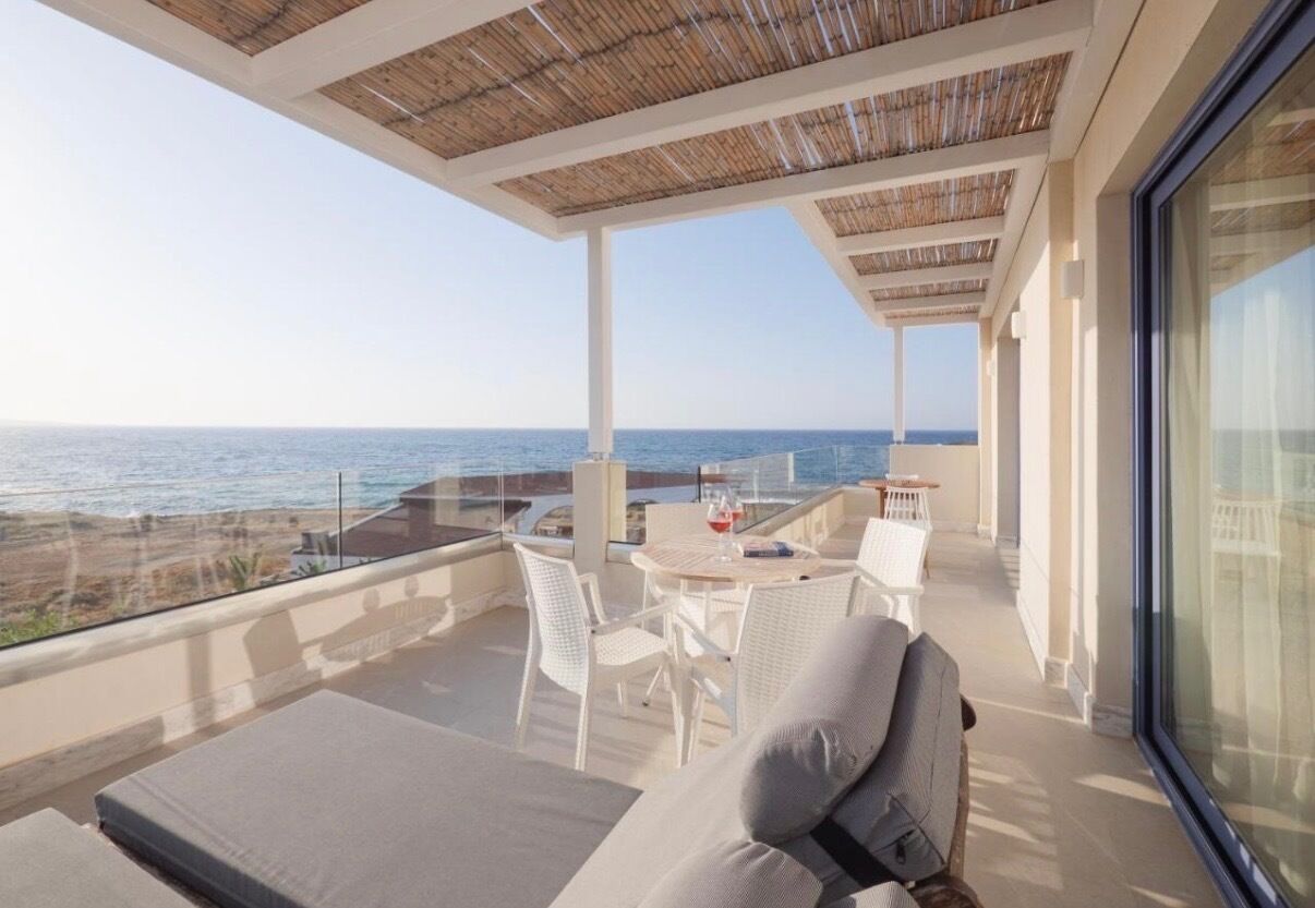 Un balcon avec vue sur la mer, une table avec des chaises et un canapé.
