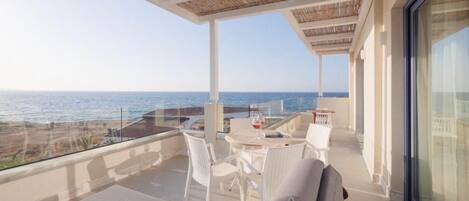 Un balcon avec vue sur la mer, une table avec des chaises et un canapé.