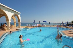 Relax by the pool surrounded by lounge chairs and umbrellas, with a covered seating area offering shade and a view.
