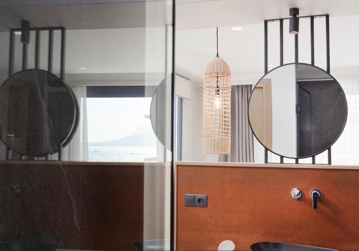 A modern bathroom with a large mirror, a round sink, and a hanging light fixture.