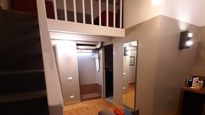 A modern living room with a staircase leading to an upper level, a sofa, and a small table with a lamp. - Assunta Domus (Rome)