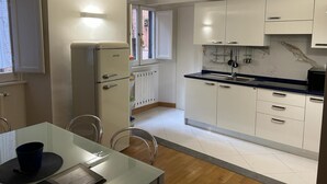 A modern kitchen with white cabinets, a built-in stove, and a window overlooking the street. - Assunta Domus (Rome)