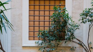 A courtyard with a fountain, potted plants, and a window with bars. - Assunta Domus (Rome)