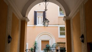An arched entrance with a gate, potted plants, and a hanging lantern. - Assunta Domus (Rome)