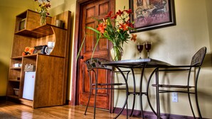 A dining area with a wooden table, chairs, a vase with flowers, and a painting on the wall. - Motel Le JoliBourg (Saint-Sauveur)