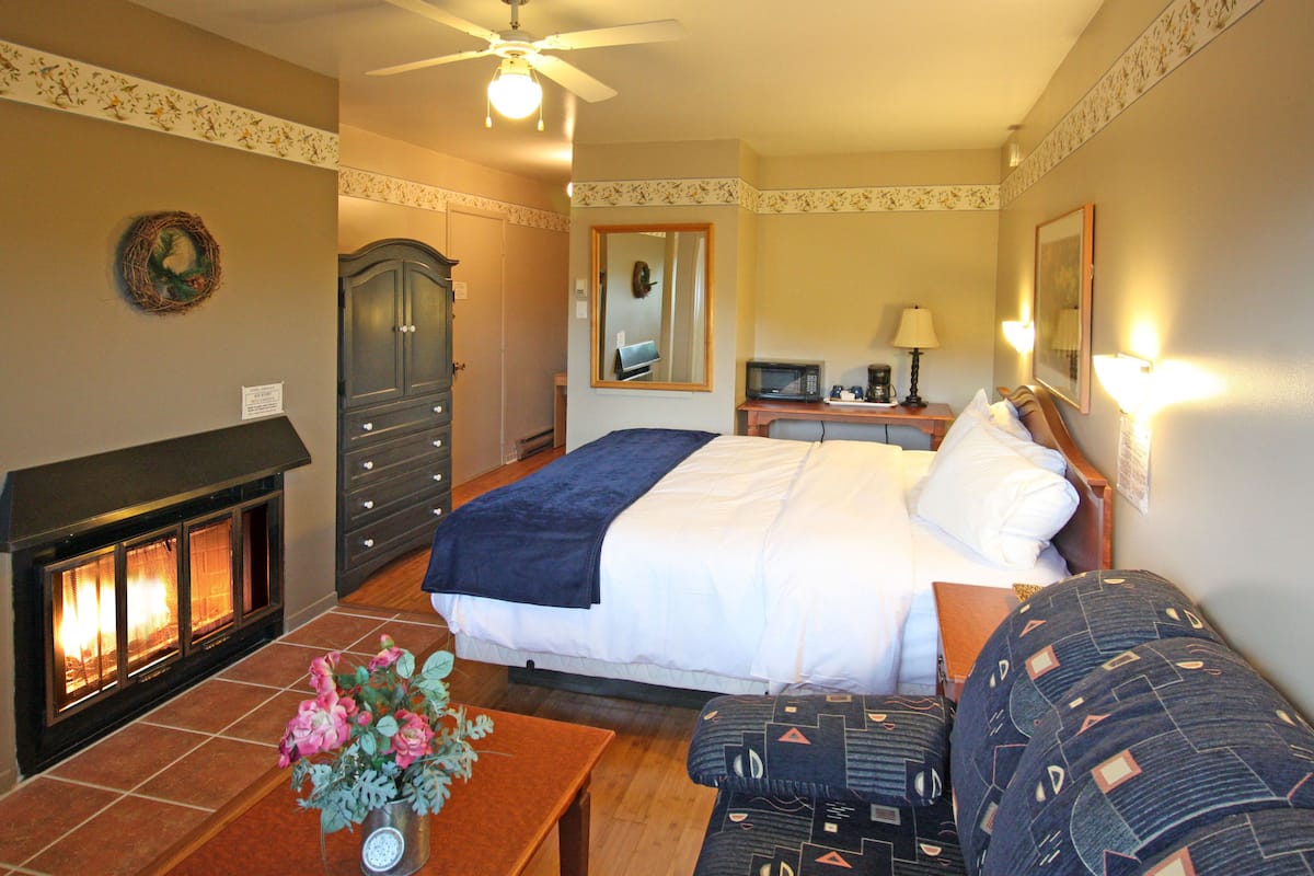 Een hotelkamer met een open haard, een bed, een bureau en een bank.