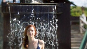 A woman in a swimming pool with a waterfall feature behind her. - Motel Le JoliBourg (Saint-Sauveur)