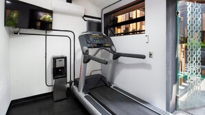 A gym with a treadmill, a water dispenser, and a wall-mounted TV. - Hotel MX aeropuerto CDMX, Trademark Collection by Wyndham (Mexico City)