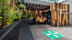 A modern building entrance with a wooden facade, a green directional arrow on the ground, and a motivational quote on the wall. - Hotel MX aeropuerto CDMX, Trademark Collection by Wyndham (Mexico City)