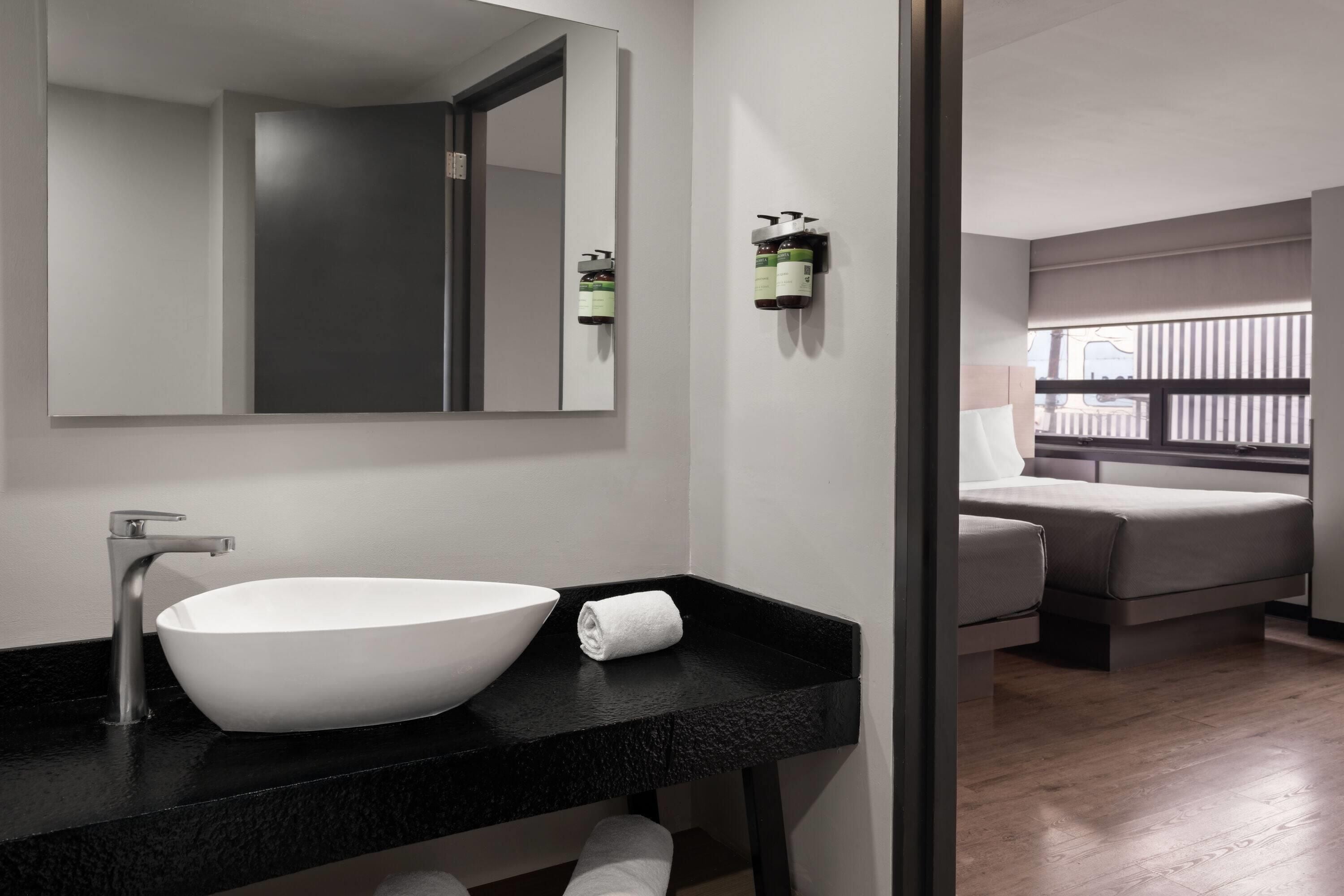 A modern bathroom with a large white sink, a mirror, and a towel on the counter.