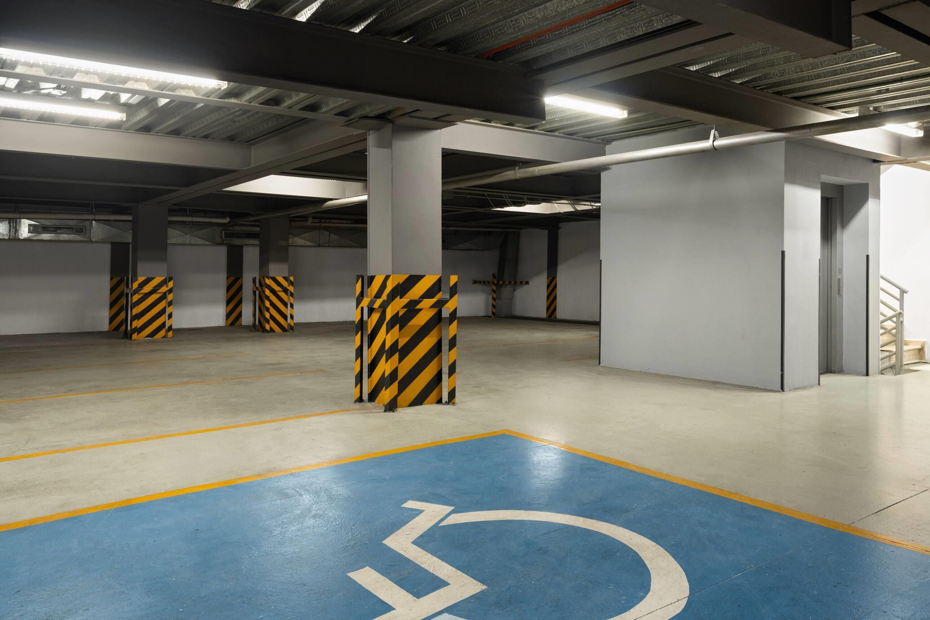 A parking garage with marked handicapped parking spaces and a stairwell.