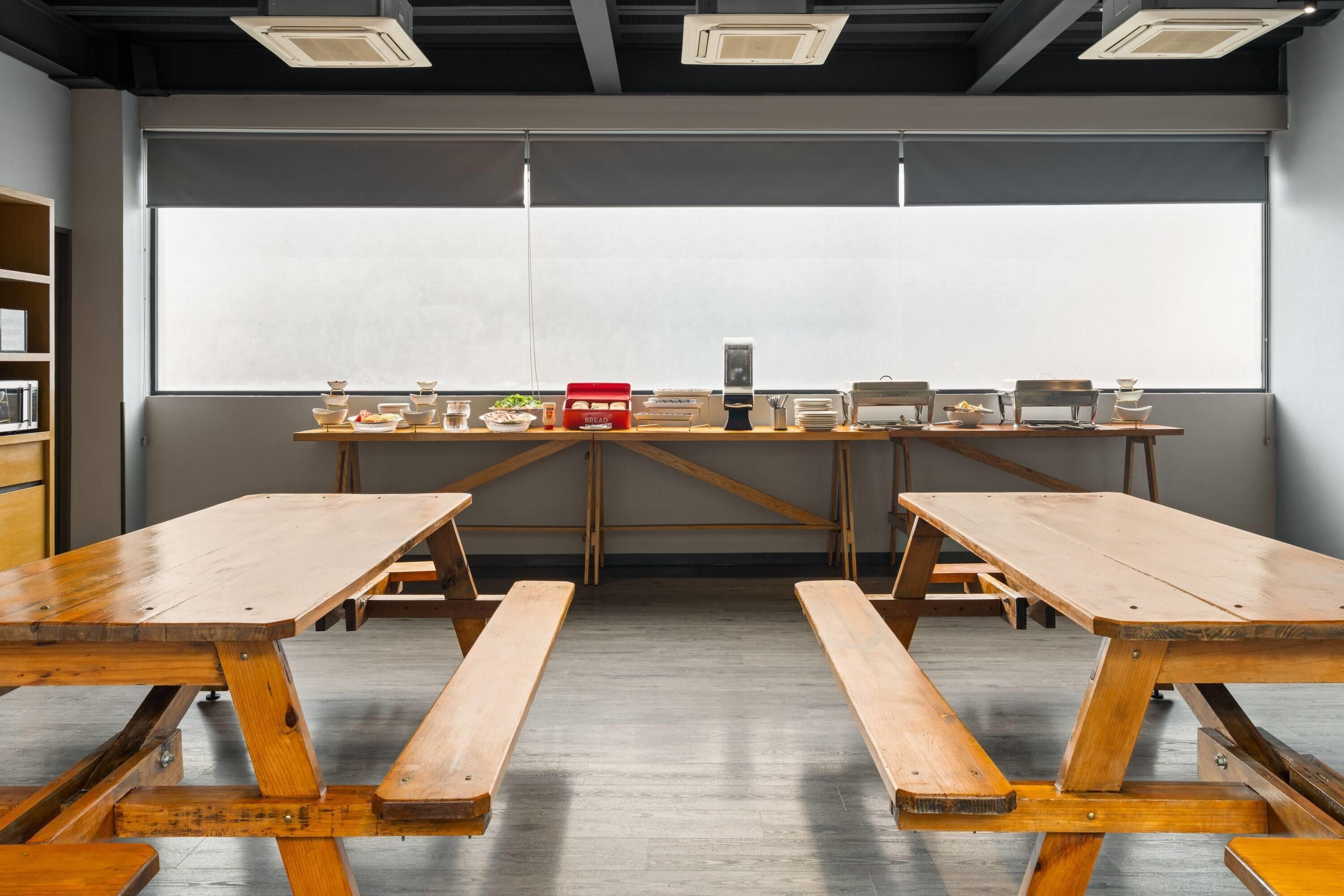 A conference room with two wooden tables, a whiteboard, and a window with blinds.