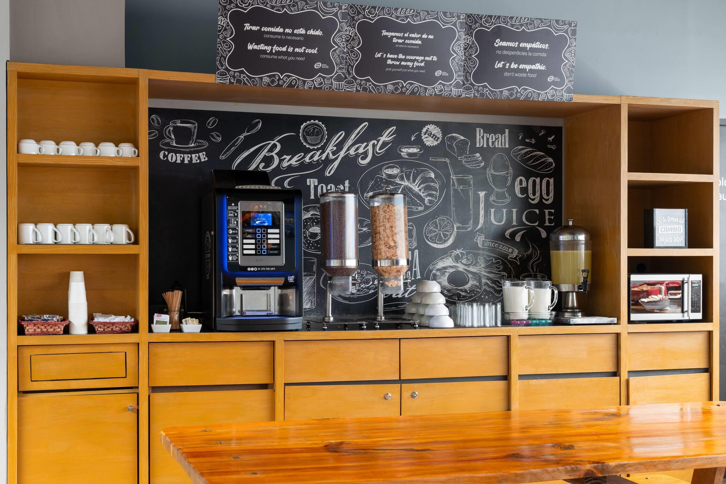 A breakfast bar with a coffee machine, a grinder, and a juice dispenser.