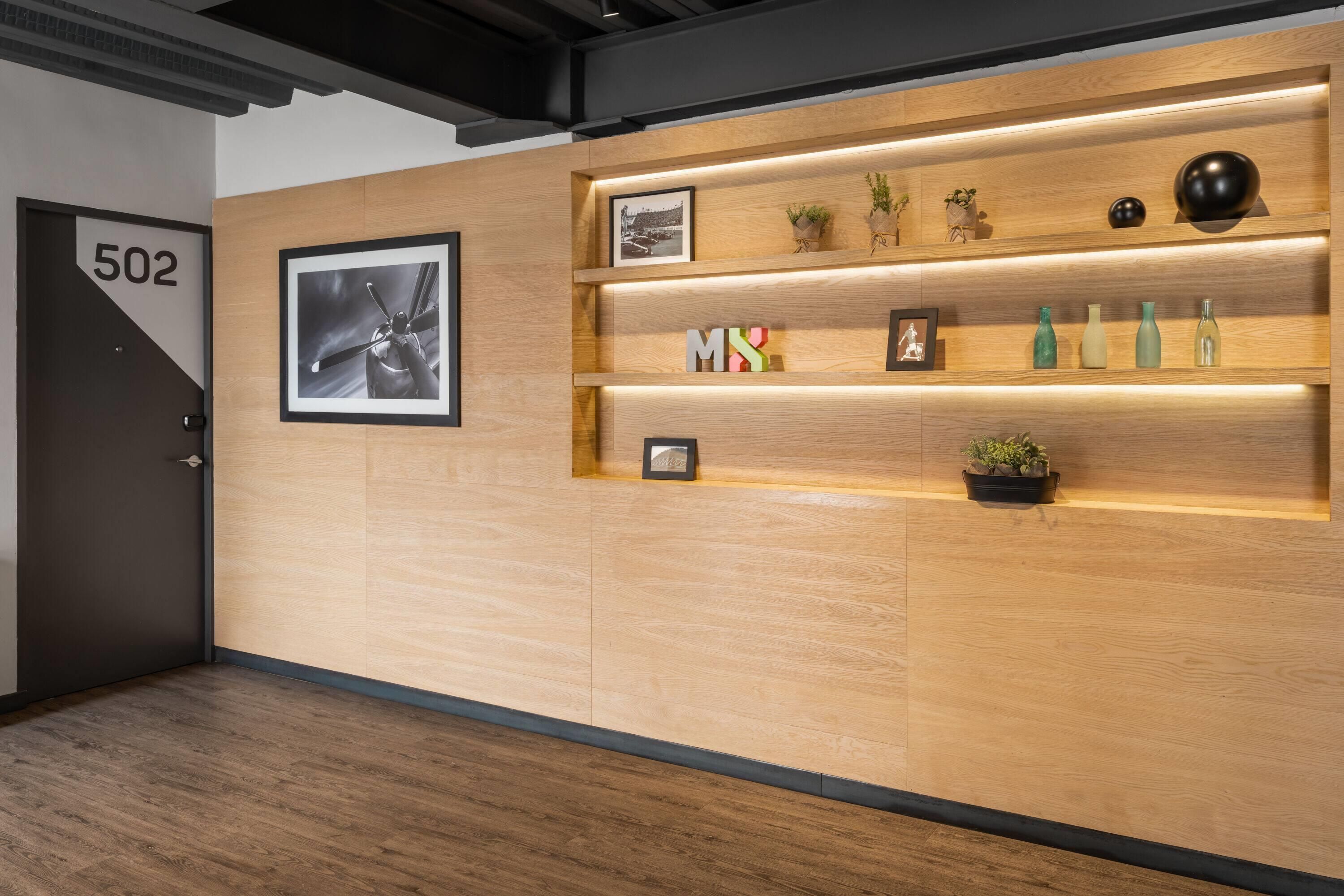 Een hotel receptie met een wand van houten panelen, een ingelijst foto, het nummer '502' op de deur en een plank met decoratieve objecten.