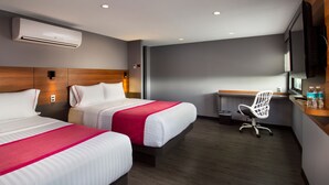 A hotel room with two beds, a desk, a chair, an air conditioner, and a TV. - Hotel MX aeropuerto CDMX, Trademark Collection by Wyndham (Mexico City)