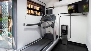A treadmill in a room with a window, a water dispenser, and a television mounted on the wall. - Hotel MX aeropuerto CDMX, Trademark Collection by Wyndham (Mexico City)