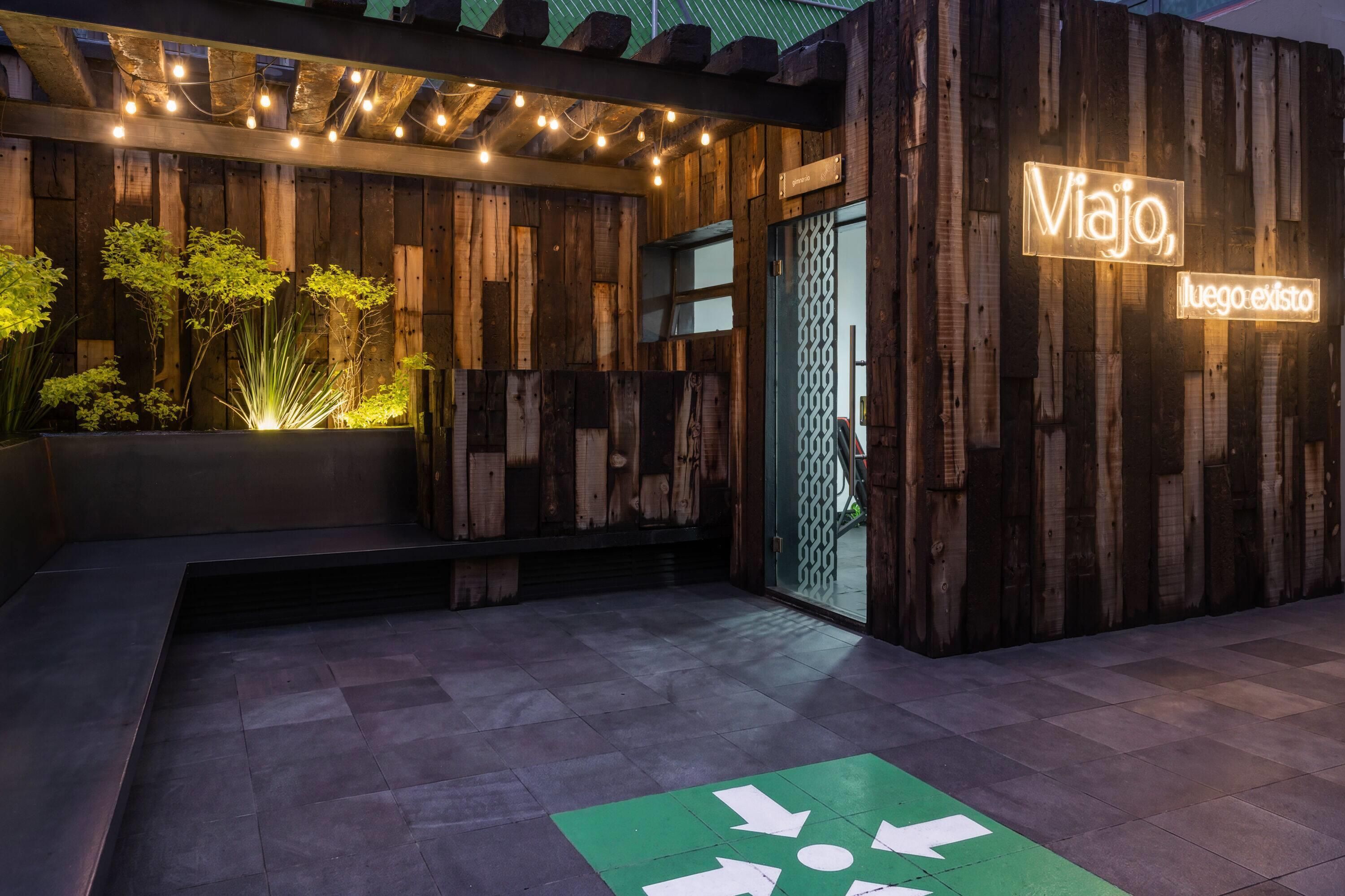A building facade with a wooden exterior, a neon sign reading 'Viajito,' and a green directional arrow on the ground.