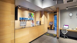 A reception area with wooden paneling, a receptionist desk, two HP computers, and a clock on the wall.