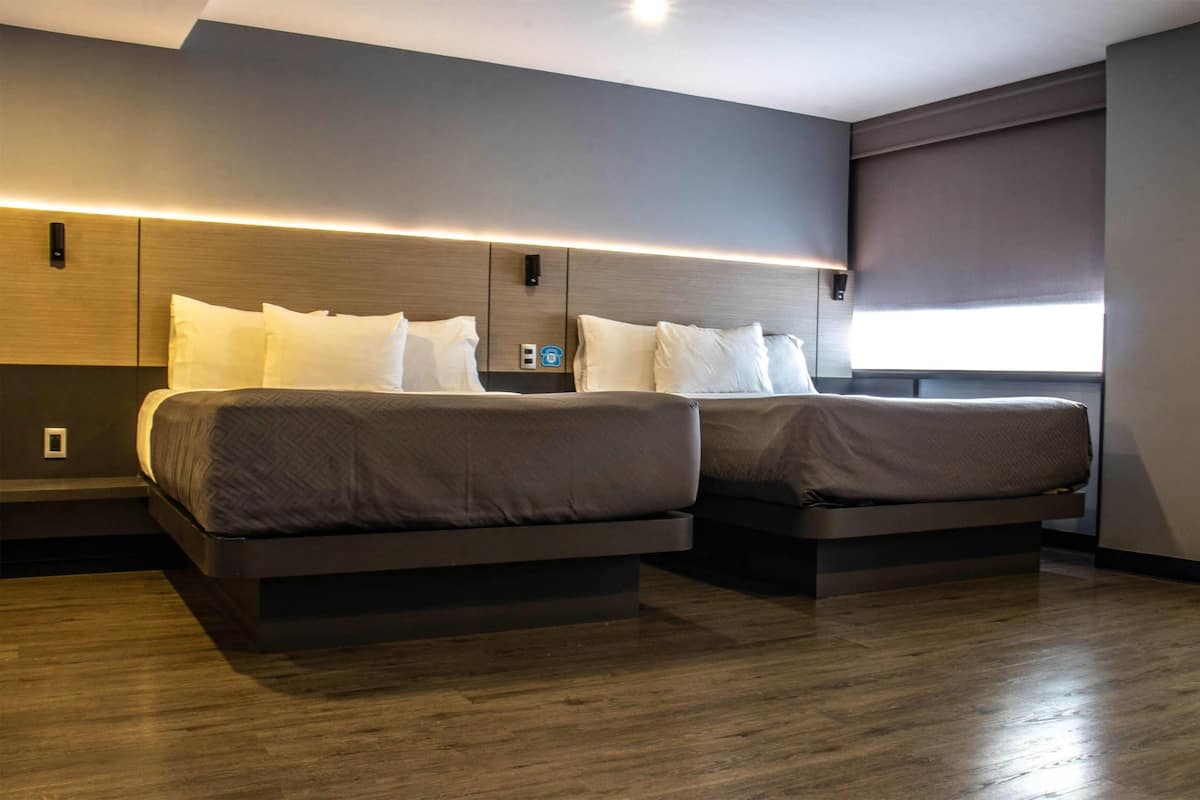 A modern hotel room with two beds, a wooden floor, and a large window with a view.