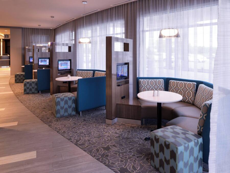 A hotel lobby with seating areas, a reception desk, and a TV screen.