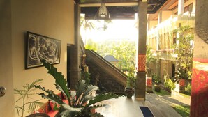 A hallway with a staircase, potted plants, and a framed picture on the wall. - Alam Terrace Cottages (Ubud)