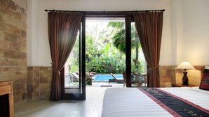 A hotel room with a bed, a view of a swimming pool, and a door leading to an outdoor area with plants. - Alam Terrace Cottages (Ubud)