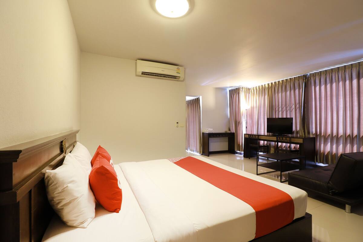 A hotel room with a bed, a TV, a desk, and a sofa.