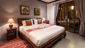 Una habitación de hotel con una cama grande, dos lámparas fijadas a la pared, una colcha a rayas rojas y blancas y una alfombra roja.