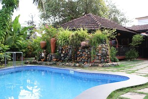 Una piscina al aire libre, sombrillas, sillones reclinables de piscina