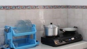 Une cuisine équipée d’une cuisinière à gaz, d’une casserole, d’une poêle et d’une grille en plastique bleue.