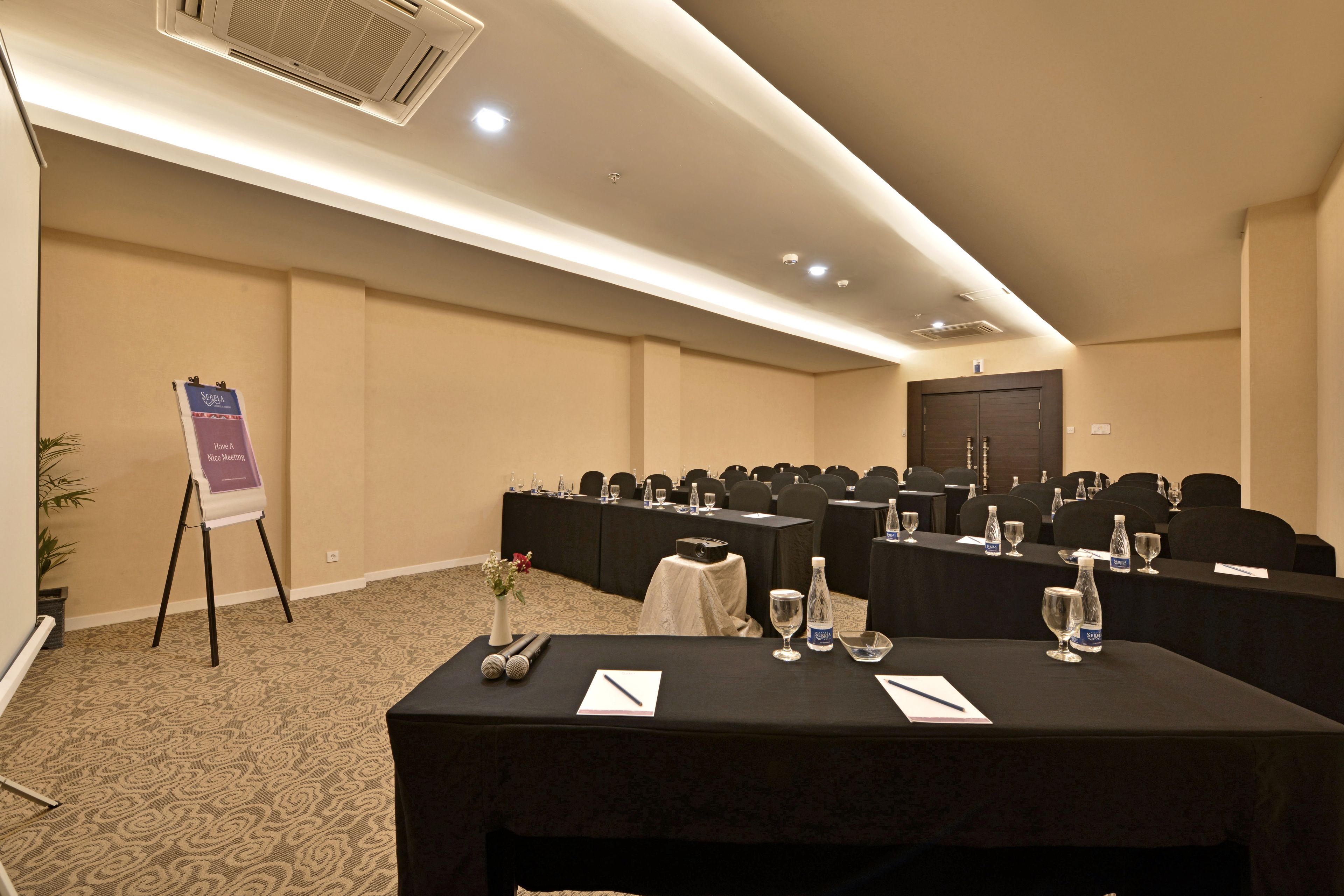 A conference room with tables set up for meetings, equipped with water bottles and notepads.