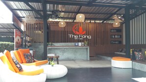 A modern outdoor seating area with wicker furniture and a wooden reception desk. - The Fong Krabi Resort (Krabi)