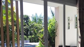 A hotel room with a large bed, a view of a swimming pool, and a balcony with plants. - The Fong Krabi Resort (Krabi)