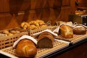 Diversos pães e doces expostos numa bancada de madeira.