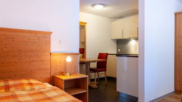 Une chambre à coucher avec une tête de lit en bois, une table de chevet avec une lampe et une couverture à carreaux sur le lit.