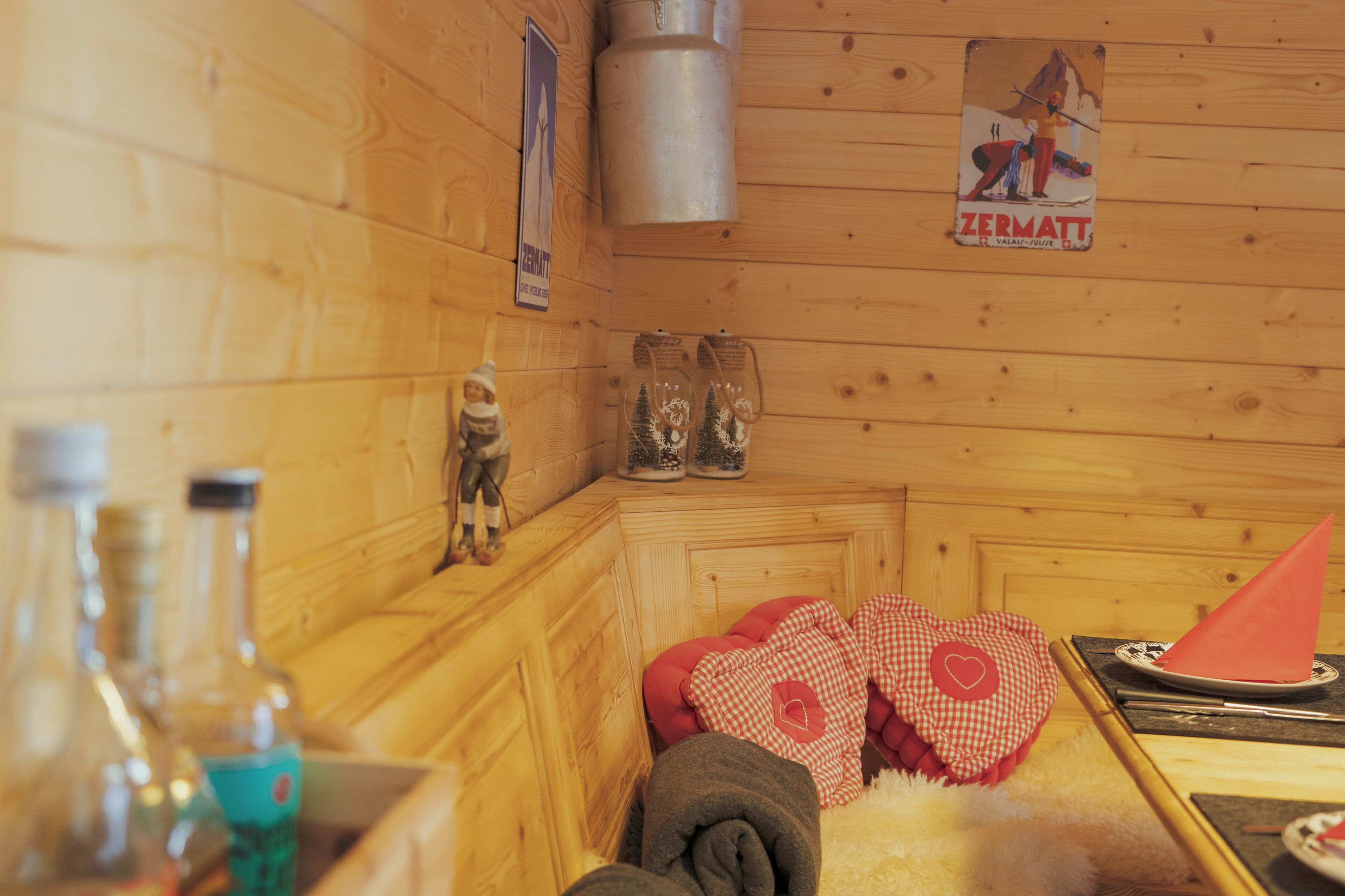 Ein Holzblockhaus-Interieur mit Sauna, Holzwänden, einem Poster und einem Tisch mit Flaschen und einem roten herzförmigen Kissen.