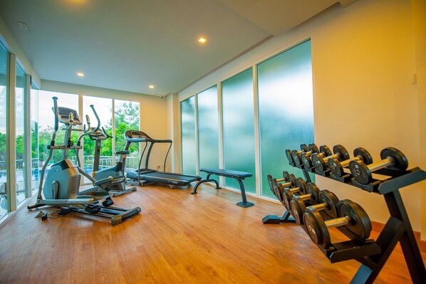 A gym with exercise equipment, large windows, and a wooden floor. - Grand Nai Harn Suites (Rawai)